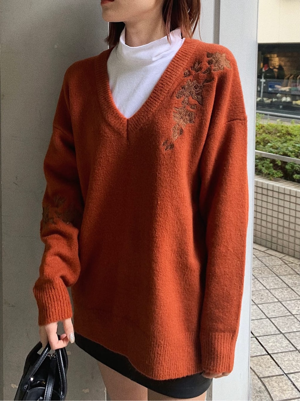 オレンジ系のニット/セーター、ブラック系のブーツ、ブラック系のスカートを着用したレディースの冬コーディネートの3枚目の写真