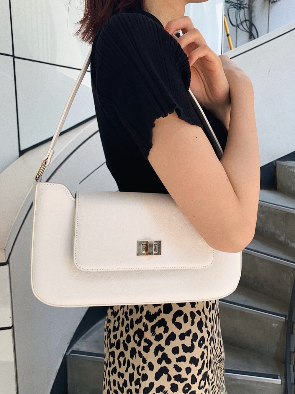 ブラック系のニット/セーター、ホワイト系のショルダーバッグ、その他のスカートを着用したレディースの春コーディネートの7枚目の写真