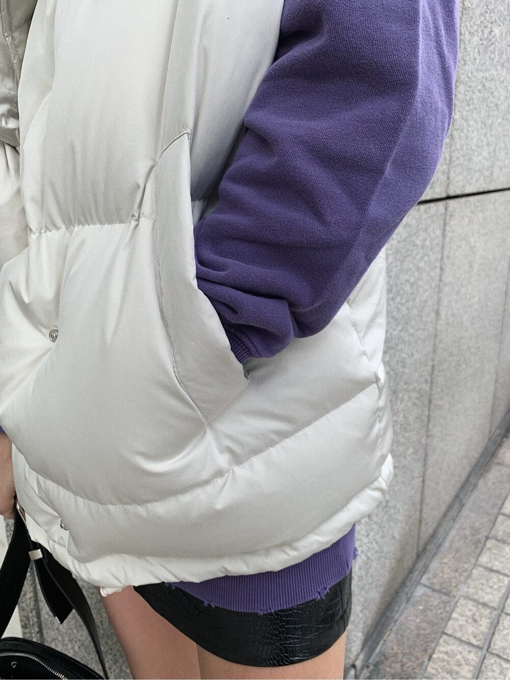 ホワイト系のダウンベスト、パープル系のスウェット、ブラック系のスカートを着用したレディースの秋コーディネートの7枚目の写真