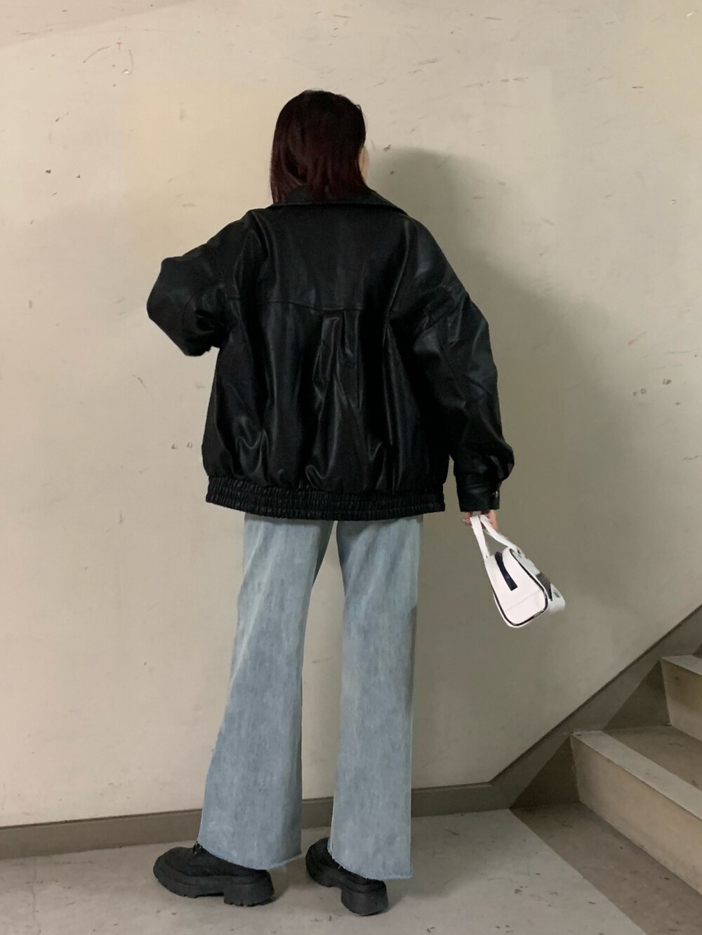 ホワイト系のニット/セーター、ブラック系のブルゾン、ブルー系のデニムパンツを着用したレディースの秋コーディネートの3枚目の写真