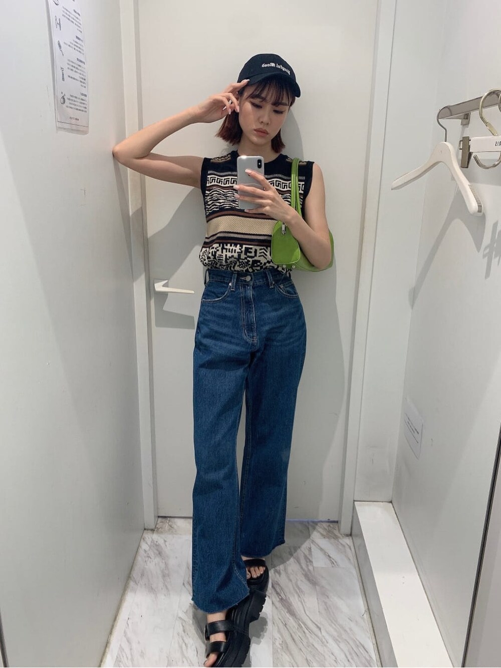 グリーン系のボストンバッグ、ブルー系のデニムパンツ、ブラック系のタンクトップを着用したレディースの夏コーディネートの2枚目の写真