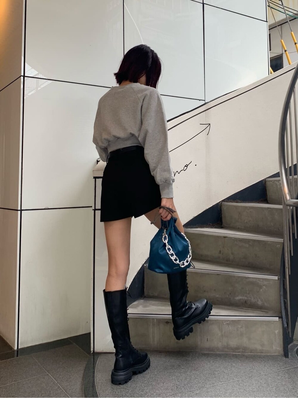 ブラック系のブーツ、ブルー系のハンドバッグ、グレー系のスウェットを着用したレディースの秋コーディネートの3枚目の写真