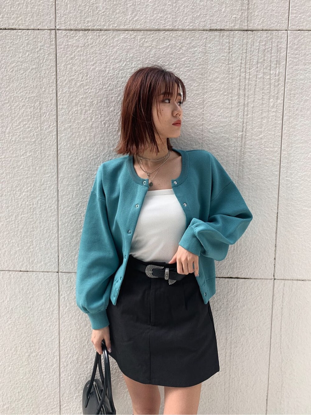 ブラック系のブーツ、ブラック系のスカート、ホワイト系のキャミソールを着用したレディースの冬コーディネートの3枚目の写真