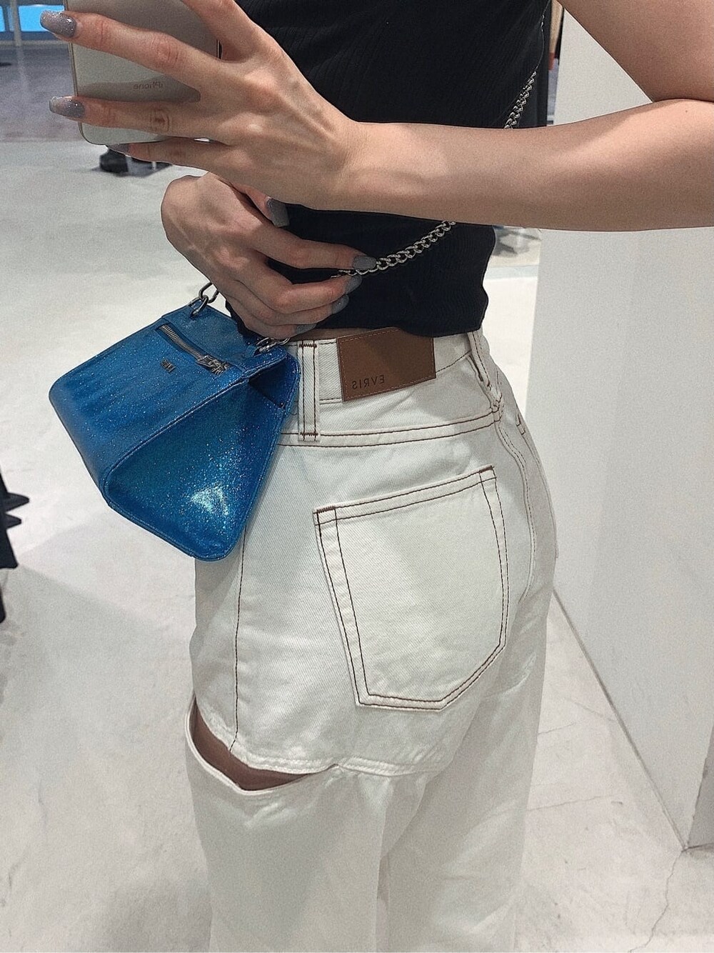 ブラック系のサンダル、ホワイト系のデニムパンツ、ブラック系のTシャツ/カットソーを着用したレディースの春コーディネートの5枚目の写真