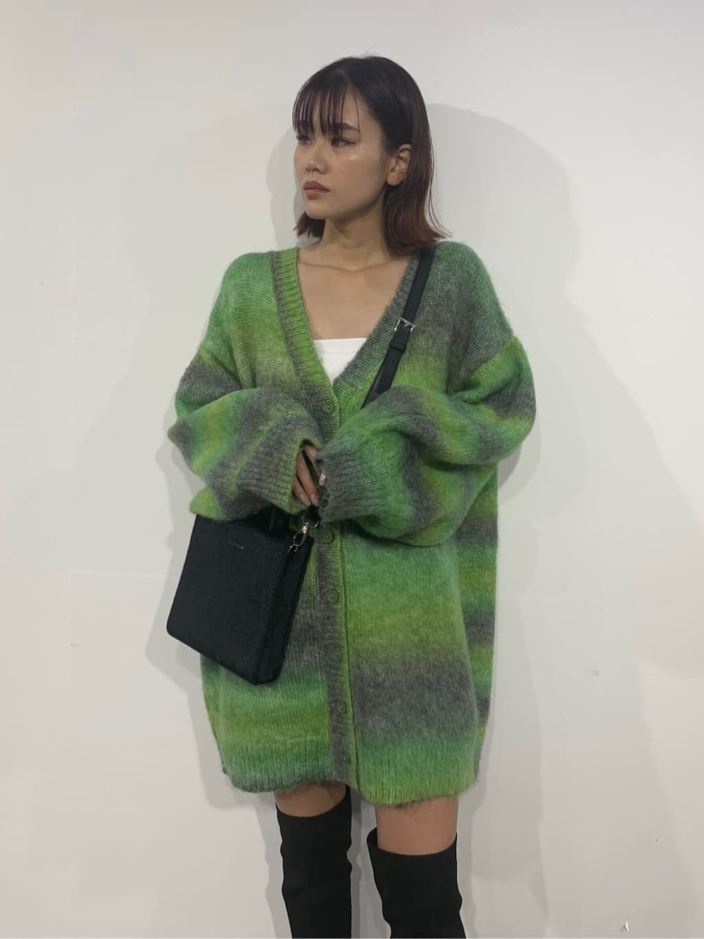 グリーン系のカーディガン/ボレロ、ブラック系のブーツ、ブラック系のショルダーバッグを着用したレディースの秋コーディネートの4枚目の写真