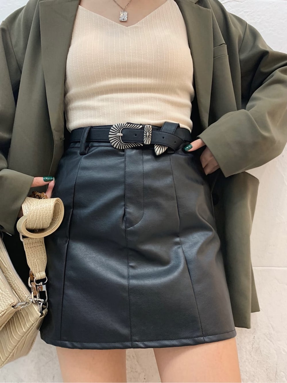 ホワイト系のキャミソール、ベージュ系のテーラードジャケット、ブラック系のブーツを着用したレディースの秋コーディネートの5枚目の写真