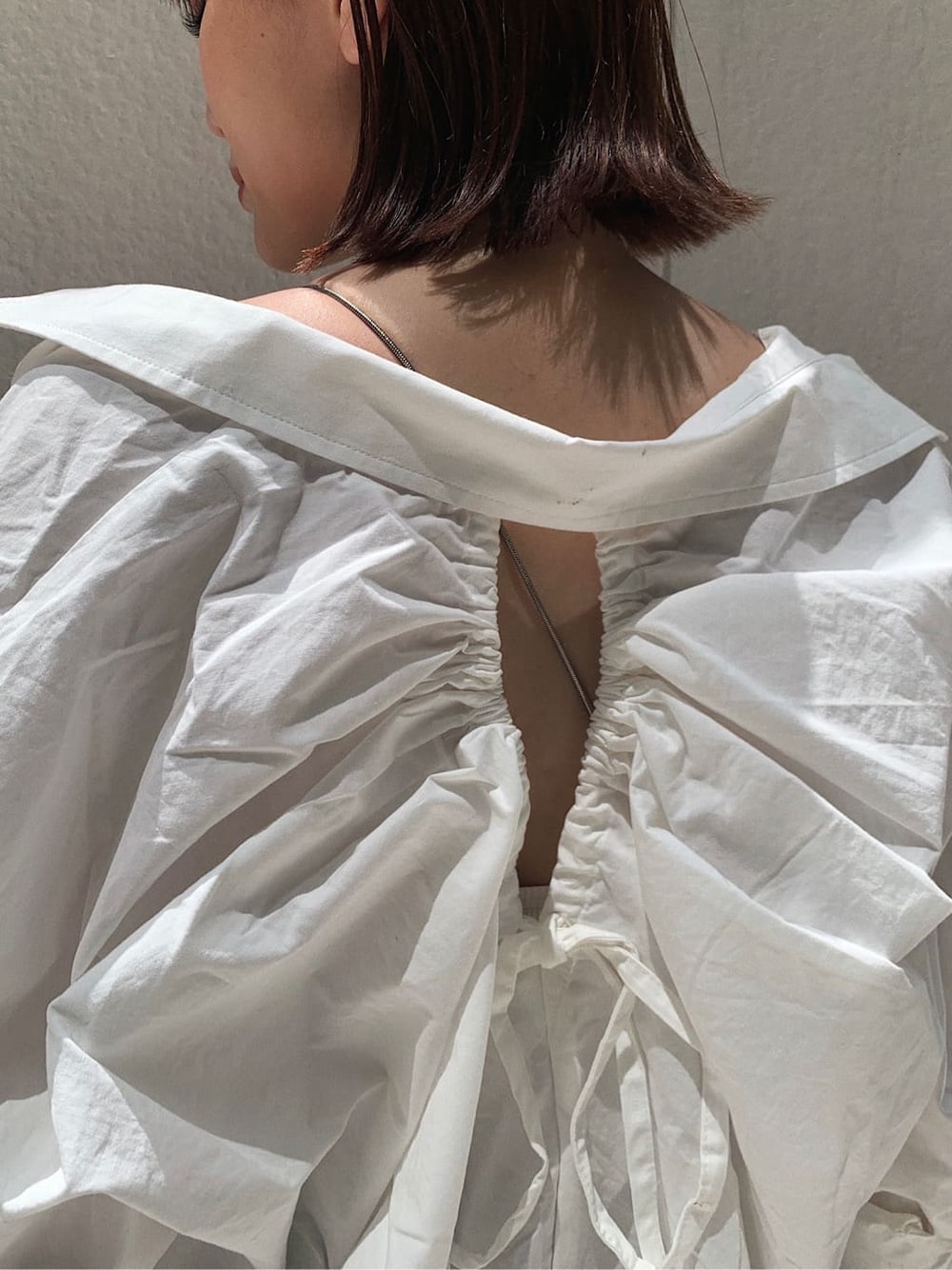 ブラウン系のデニムパンツ、ホワイト系のキャミソール、ブラック系のサンダルを着用したレディースの秋コーディネートの4枚目の写真