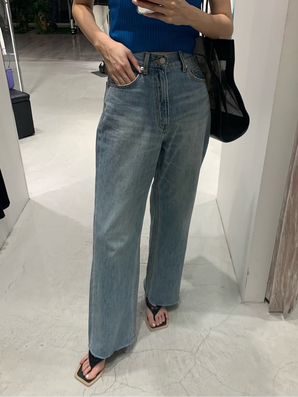 ブラック系のサンダル、ブルー系のデニムパンツ、ブラック系のトートバッグを着用したレディースの夏コーディネートの4枚目の写真