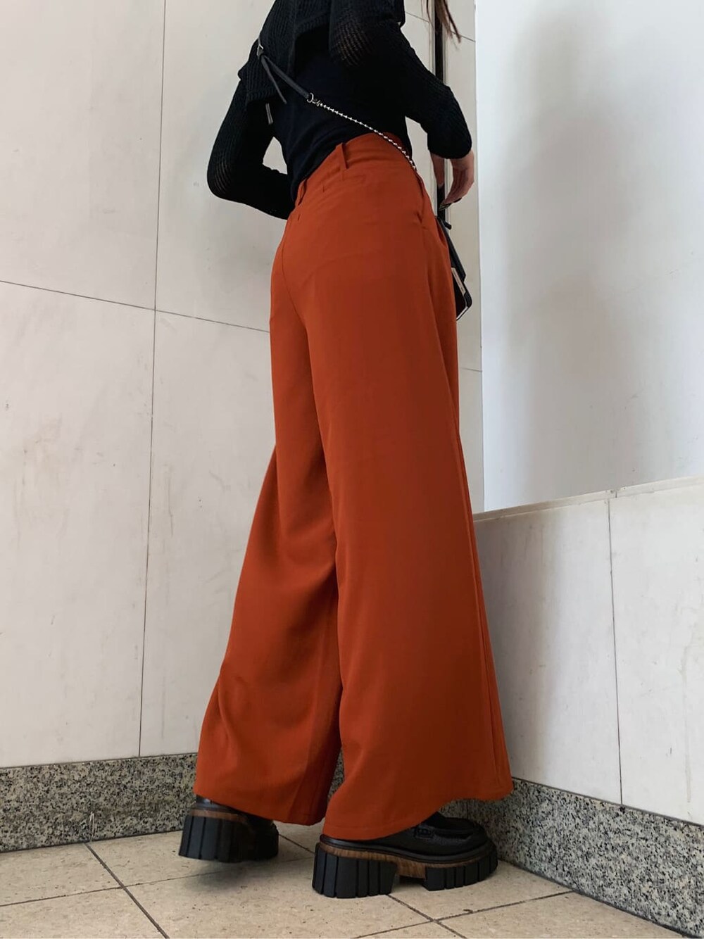 オレンジ系のその他パンツ、ブラック系のローファー、ブラック系のスマホケース/カバーを着用したレディースの秋コーディネートの4枚目の写真