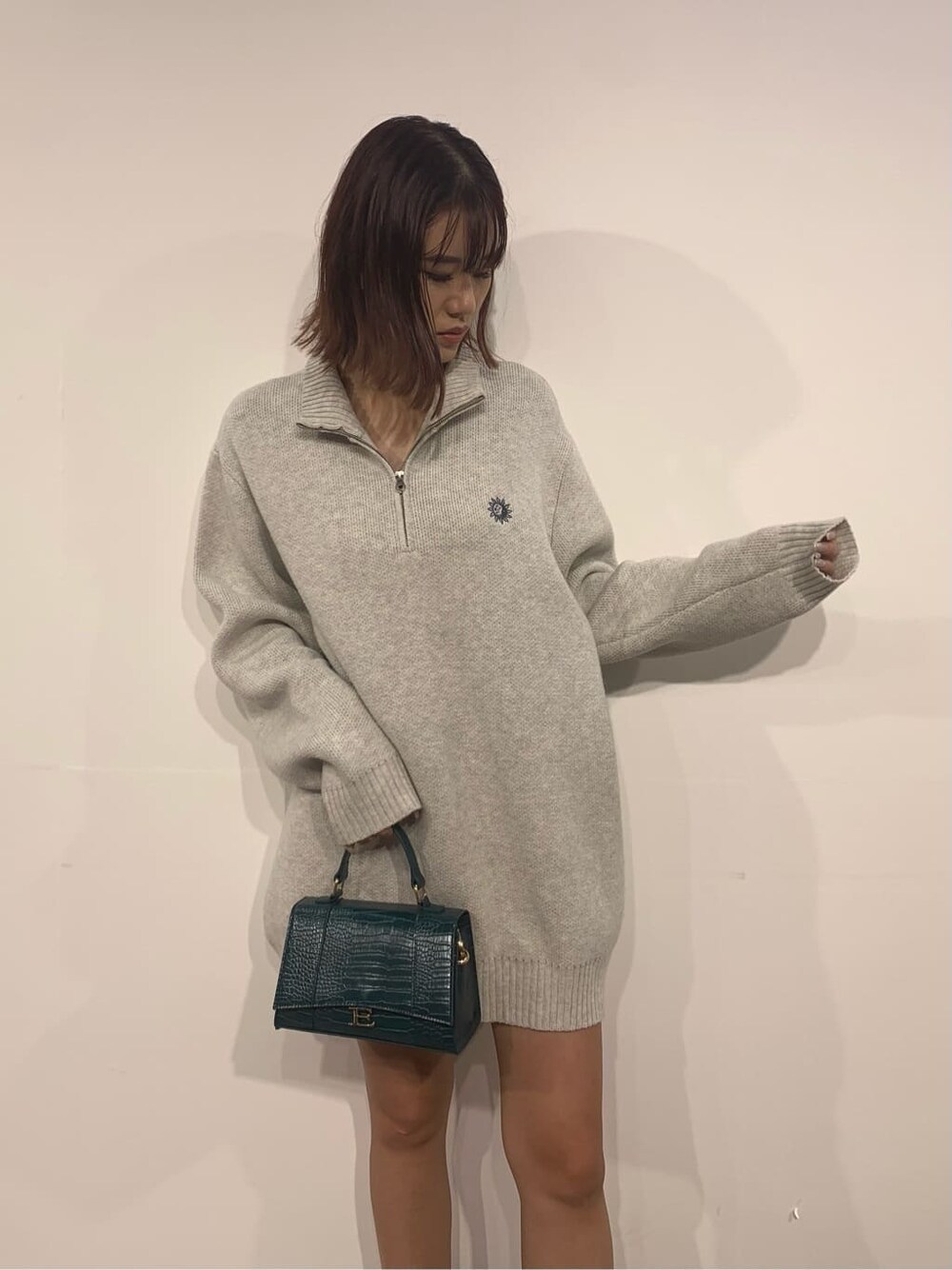 グレー系のニット/セーター、ブラック系のブーツ、グリーン系のショルダーバッグを着用したレディースの秋コーディネートの5枚目の写真