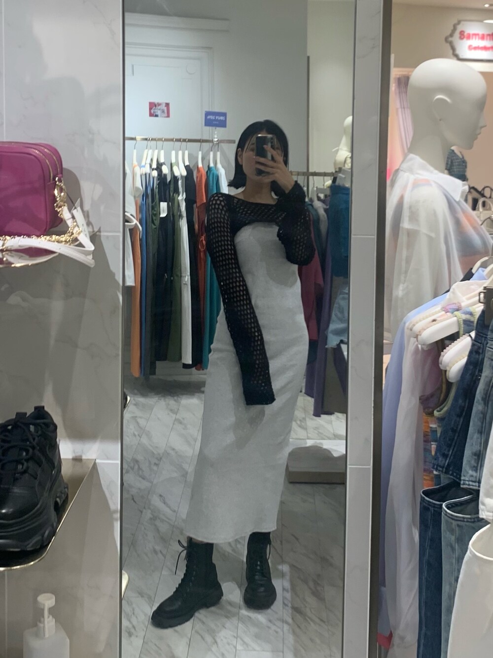 グレー系のワンピース、ブラック系のニット/セーター、ブラック系のブーツを着用したレディースの春コーディネートの2枚目の写真