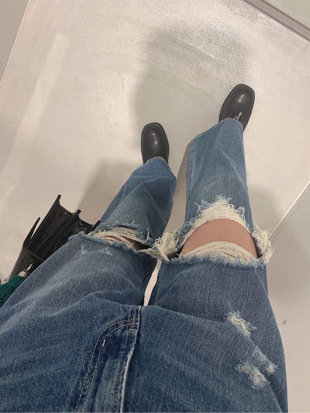 ブラック系のブーツ、ブルー系のデニムパンツ、グリーン系のニット/セーターを着用したレディースの春コーディネートの6枚目の写真