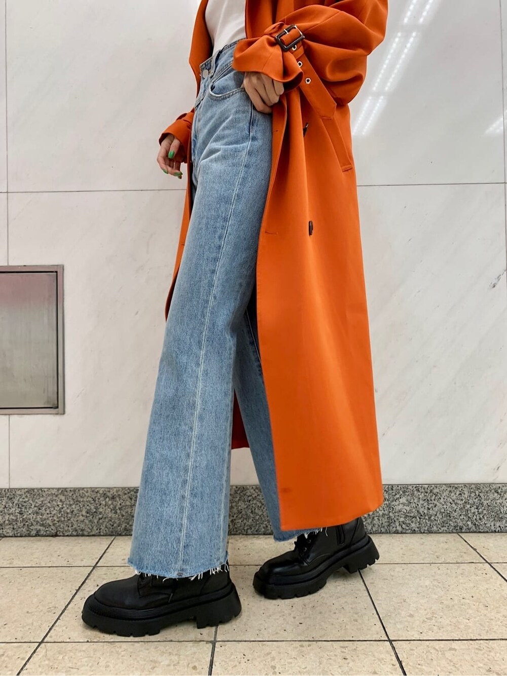 ブラック系のショルダーバッグ、オレンジ系のトレンチコート、ブルー系のデニムパンツを着用したレディースの冬コーディネートの8枚目の写真