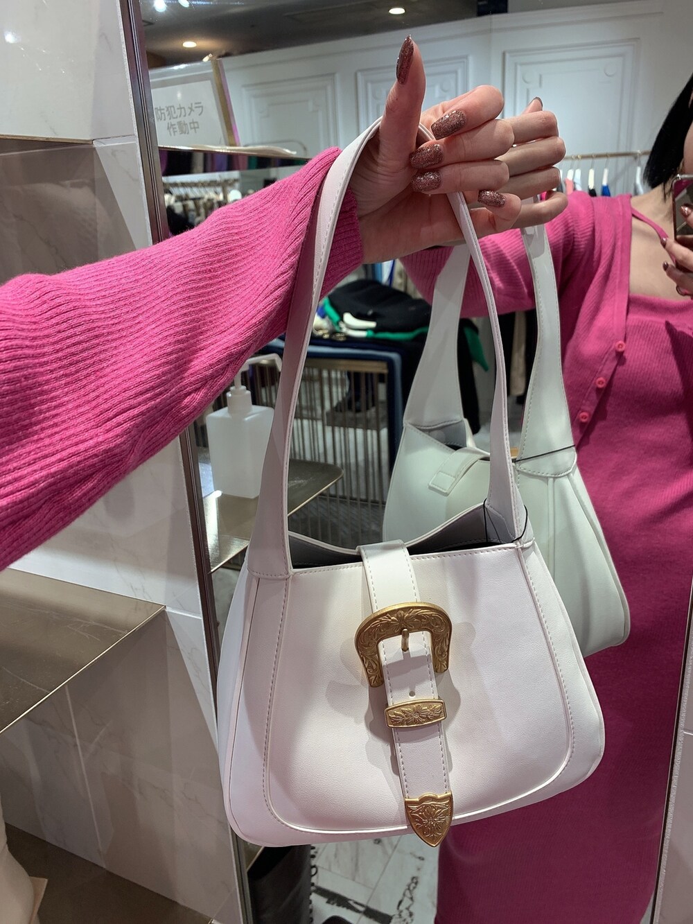 ホワイト系のハンドバッグ、ピンク系のワンピース、ブラック系のブーツを着用したレディースの冬コーディネートの6枚目の写真