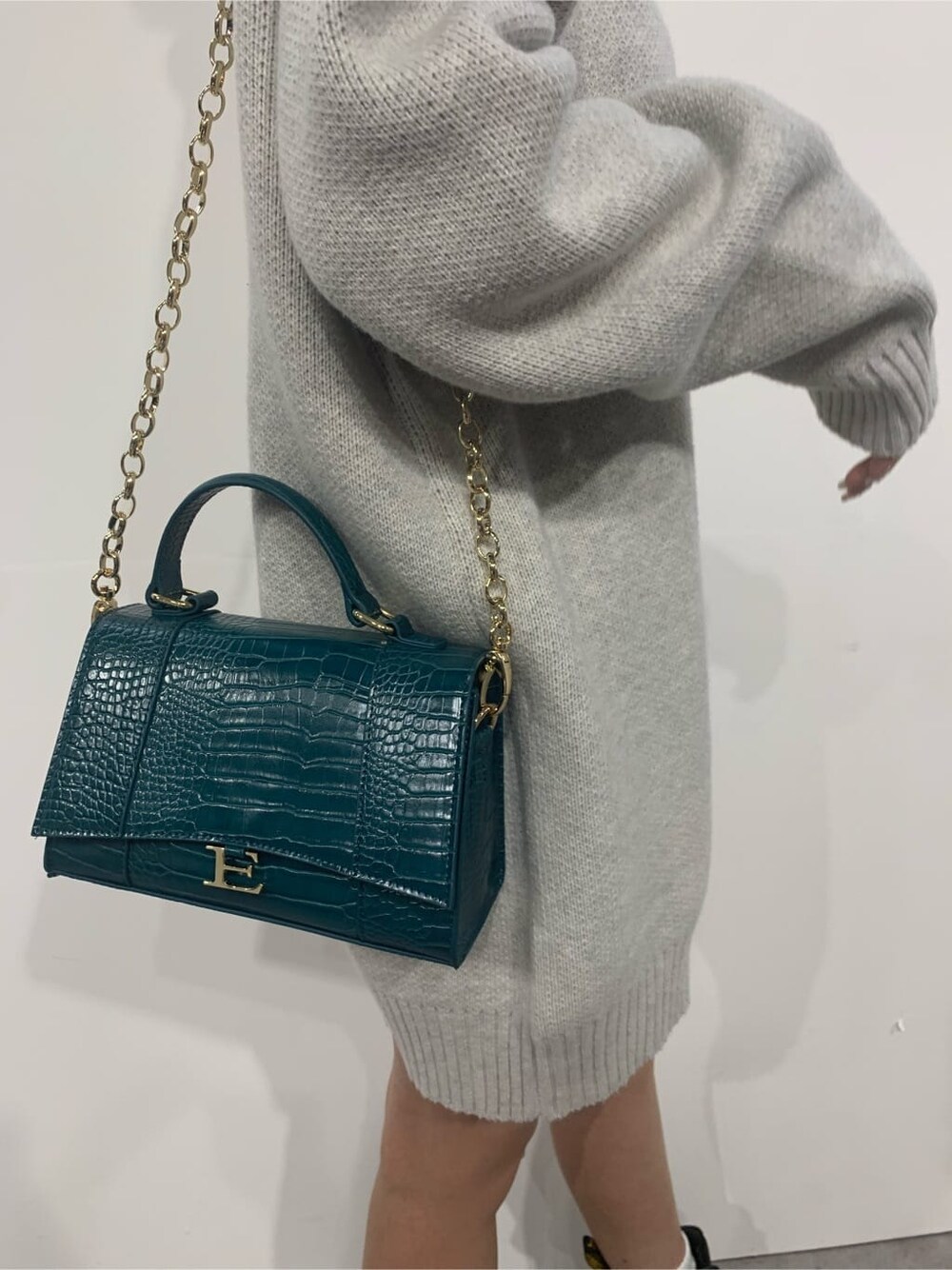 グレー系のニット/セーター、ブラック系のブーツ、グリーン系のショルダーバッグを着用したレディースの秋コーディネートの8枚目の写真