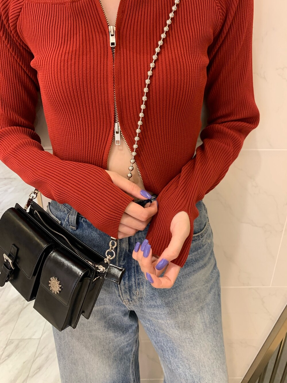 レッド系のニット/セーター、ブラック系のショルダーバッグ、ブルー系のデニムパンツを着用したレディースの夏コーディネートの5枚目の写真