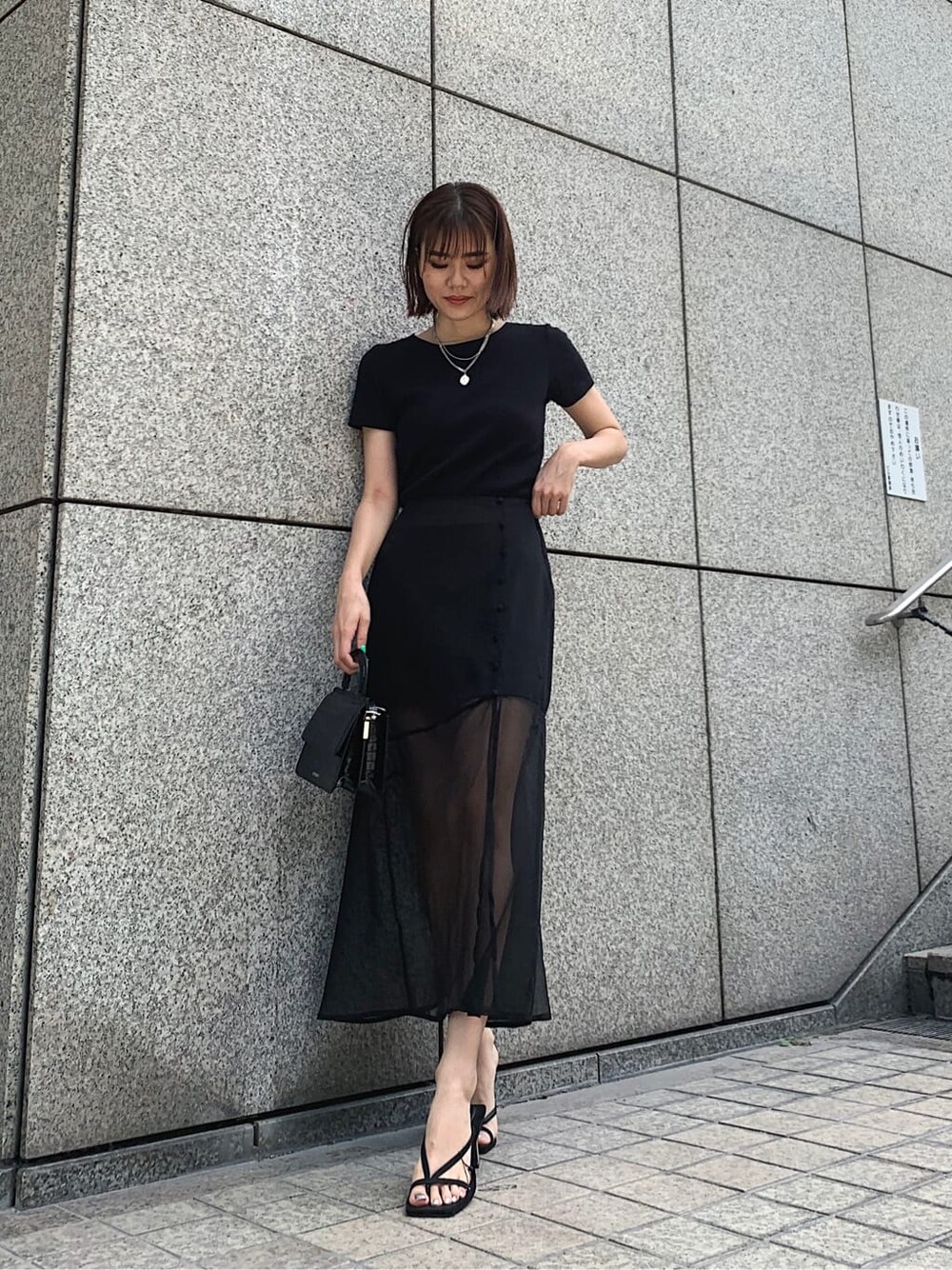 ブラック系のスカート、ブラック系のTシャツ/カットソー、ブラック系のサンダルを着用したレディースの夏コーディネートの3枚目の写真