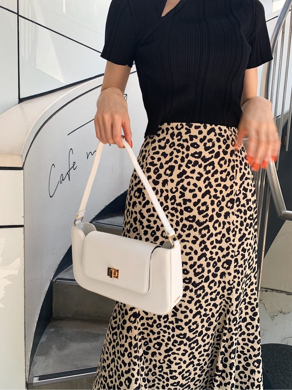 ブラック系のニット/セーター、ホワイト系のショルダーバッグ、その他のスカートを着用したレディースの春コーディネートの6枚目の写真