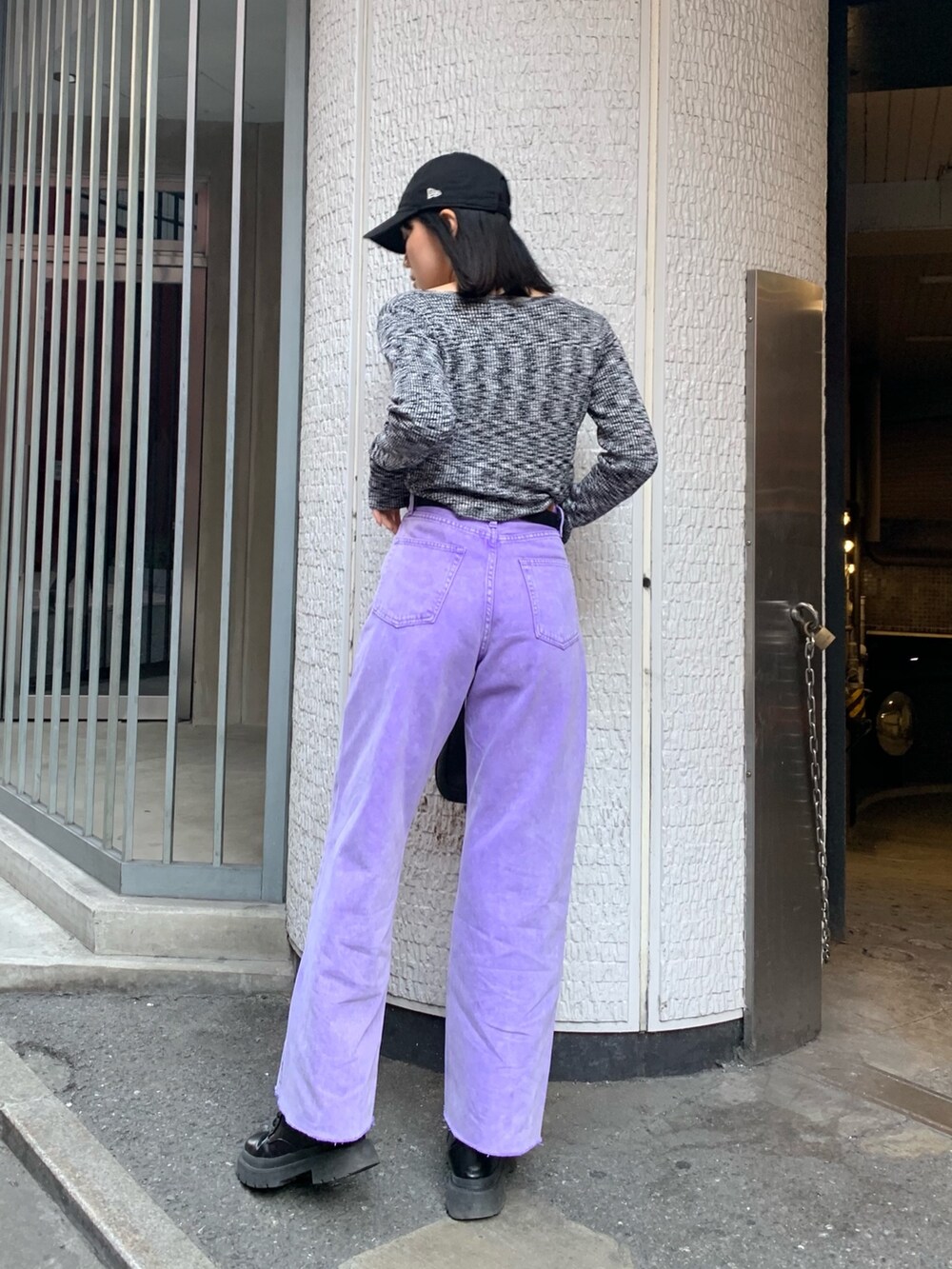 パープル系のデニムパンツ、ブラック系のニット/セーター、ブラック系のハンドバッグを着用したレディースの冬コーディネートの3枚目の写真