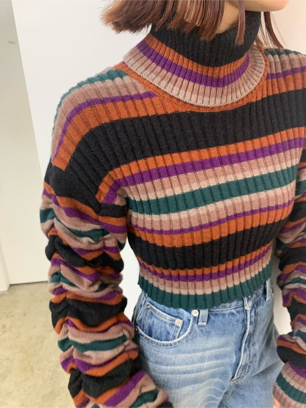 ブラック系のハンドバッグ、ブラック系のブーツ、ブルー系のデニムパンツを着用したレディースの秋コーディネートの5枚目の写真