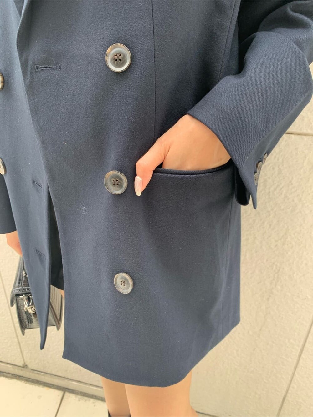 ブルー系のテーラードジャケット、ブラック系のハンドバッグ、ブラック系のブーツを着用したレディースの秋コーディネートの6枚目の写真