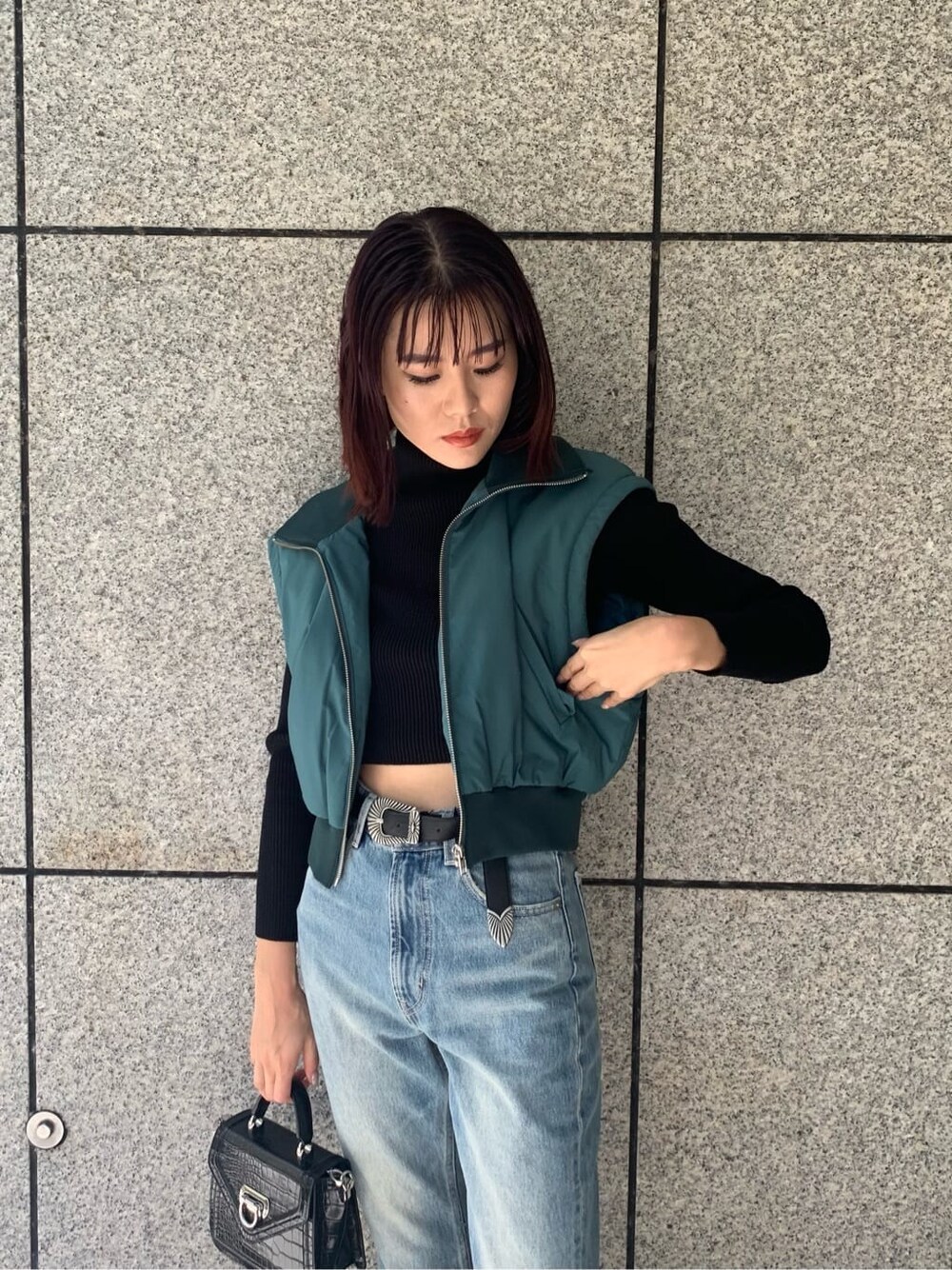 ブラック系のハンドバッグ、ブルー系のデニムパンツ、ブルー系のMA-1を着用したレディースの秋コーディネートの7枚目の写真