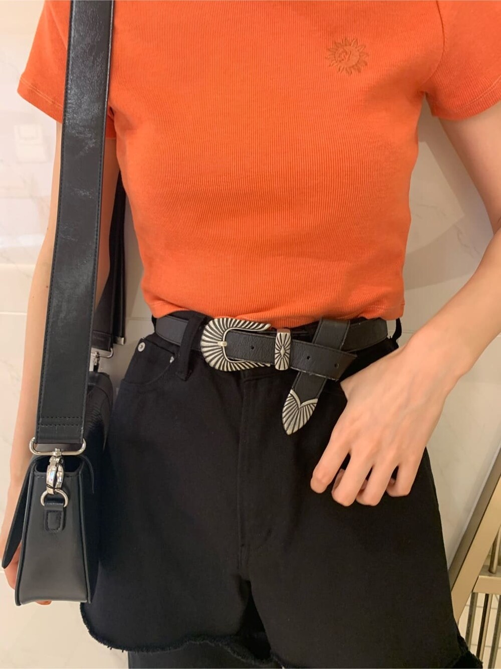 オレンジ系のTシャツ/カットソー、ブラック系のサンダル、ブラック系のショルダーバッグを着用したレディースの春コーディネートの7枚目の写真