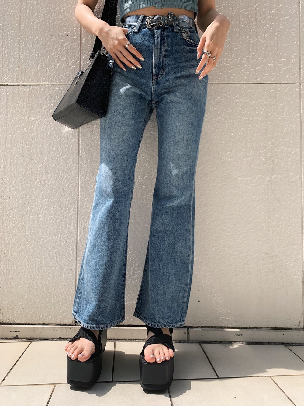ブラック系のサンダル、ブルー系のデニムパンツ、その他のベルトを着用したレディースの春コーディネートの2枚目の写真