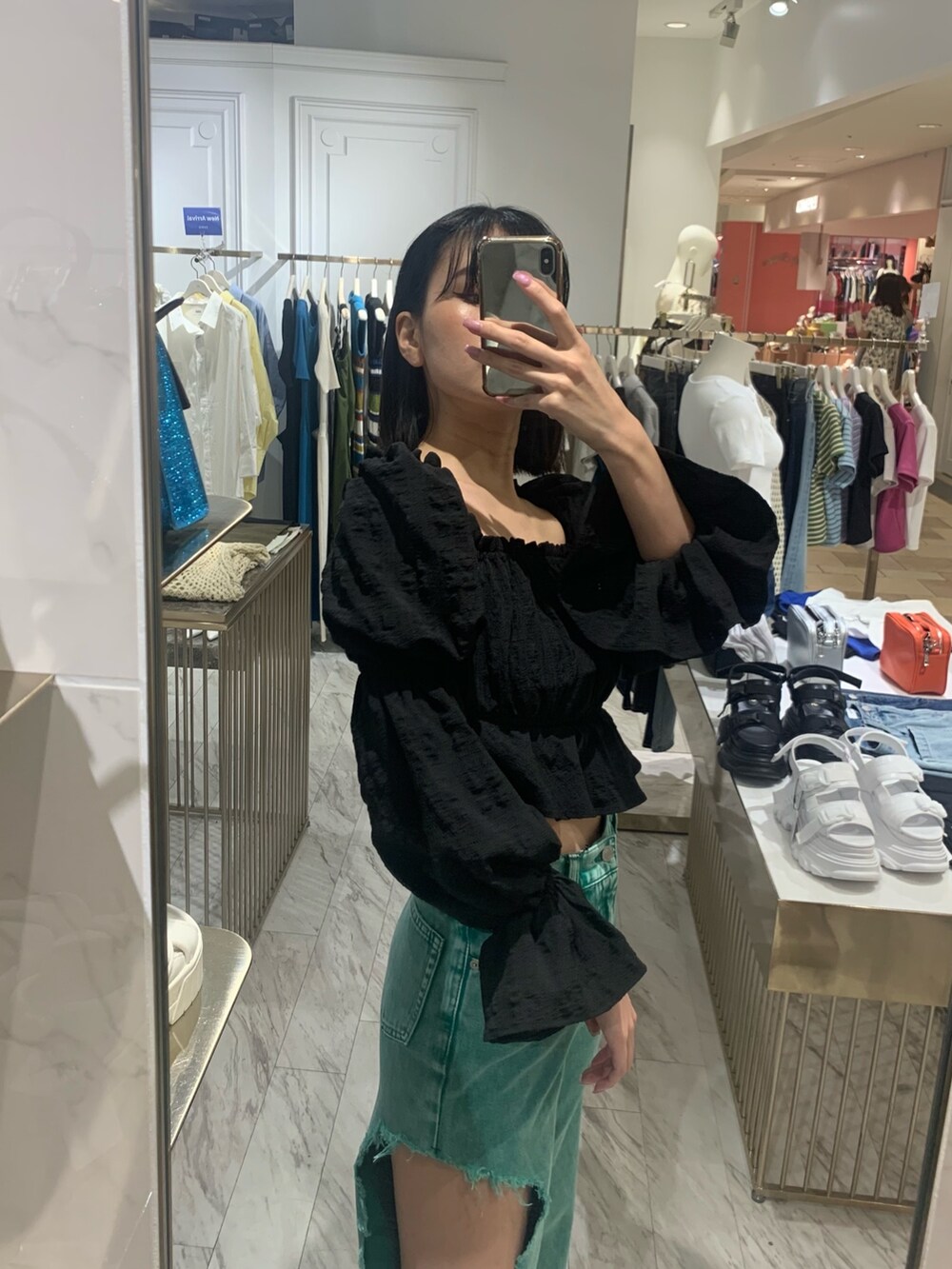 グリーン系のデニムパンツ、ブラック系のサンダル、ブラック系のシャツ/ブラウスを着用したレディースの春コーディネートの2枚目の写真