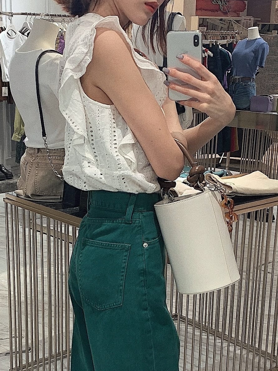 グリーン系のデニムパンツ、ホワイト系のタンクトップ、ホワイト系のサンダルを着用したレディースの春コーディネートの5枚目の写真