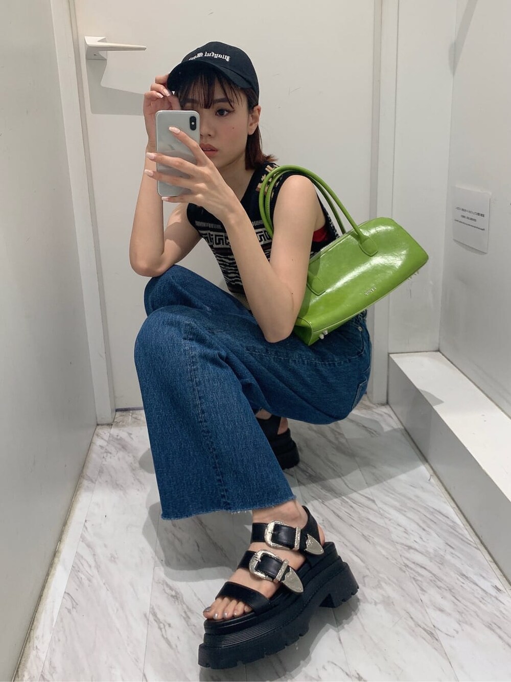 グリーン系のボストンバッグ、ブルー系のデニムパンツ、ブラック系のタンクトップを着用したレディースの夏コーディネートの8枚目の写真