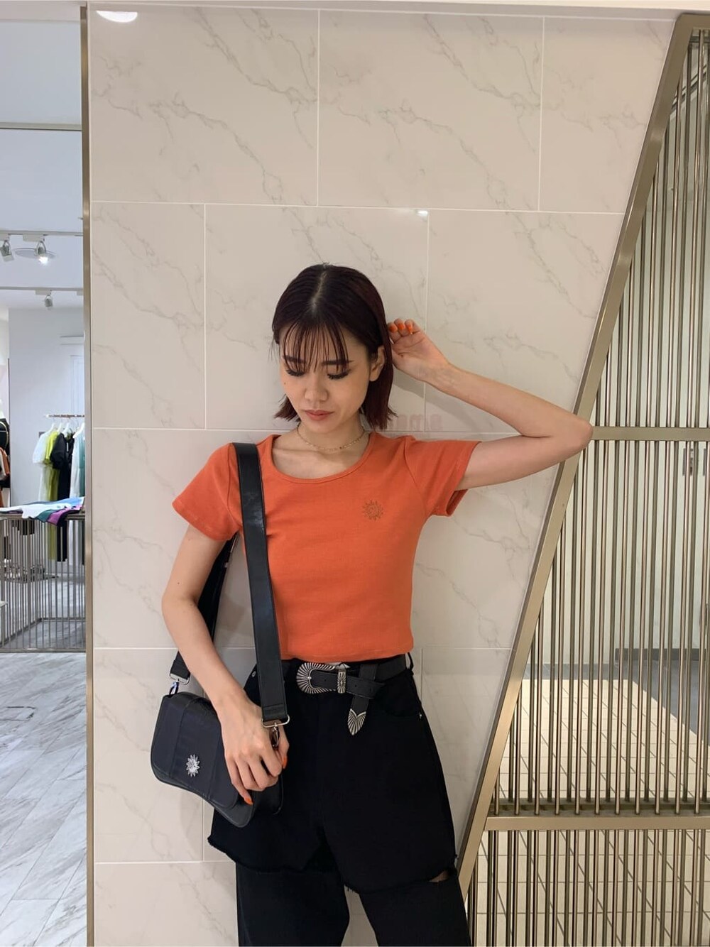 オレンジ系のTシャツ/カットソー、ブラック系のサンダル、ブラック系のショルダーバッグを着用したレディースの春コーディネートの3枚目の写真