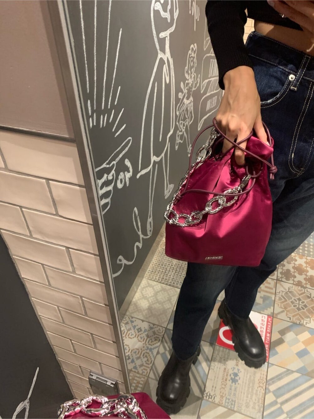 ブラック系のニット/セーター、ピンク系のハンドバッグ、ブルー系のデニムパンツを着用したレディースの秋コーディネートの6枚目の写真