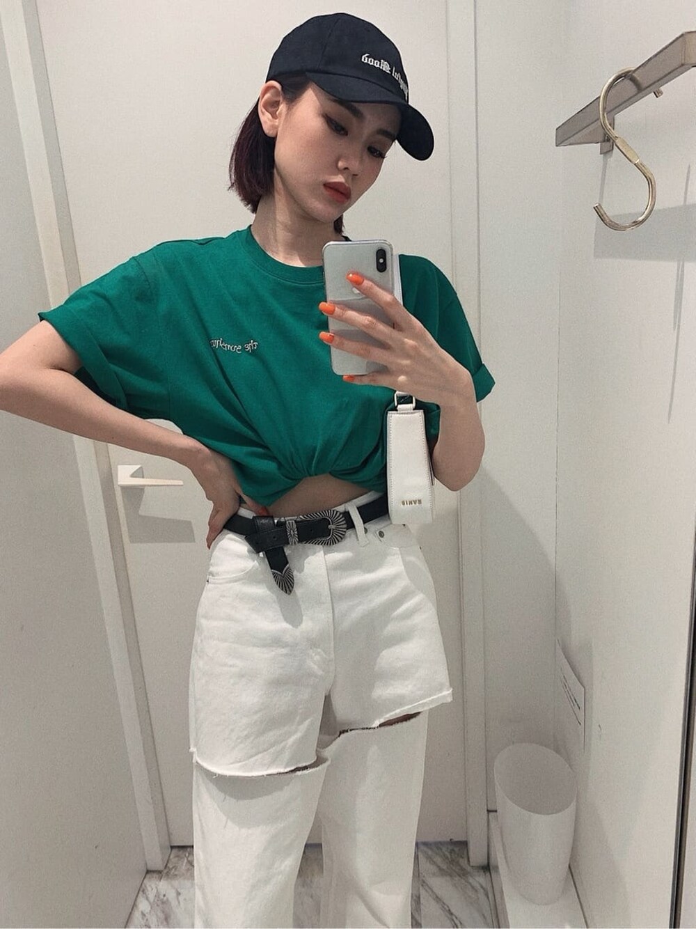 ブラック系のスニーカー、ホワイト系のショルダーバッグ、ホワイト系のデニムパンツを着用したレディースの春コーディネートの2枚目の写真