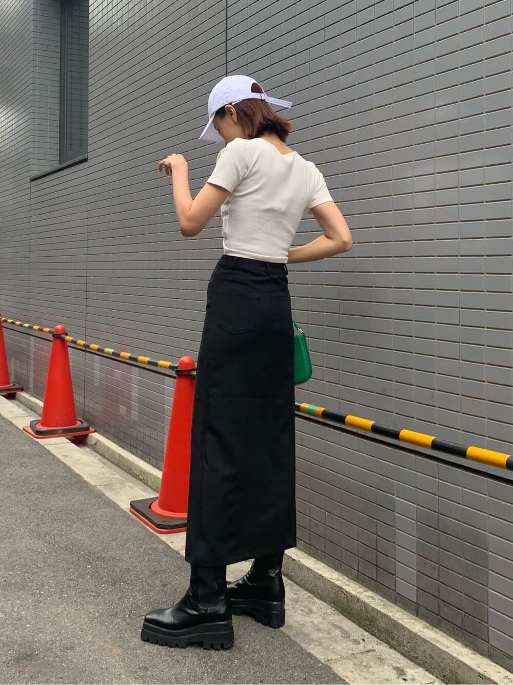 ブラック系のスカート、ブラック系のブーツ、グリーン系のショルダーバッグを着用したレディースの夏コーディネートの3枚目の写真