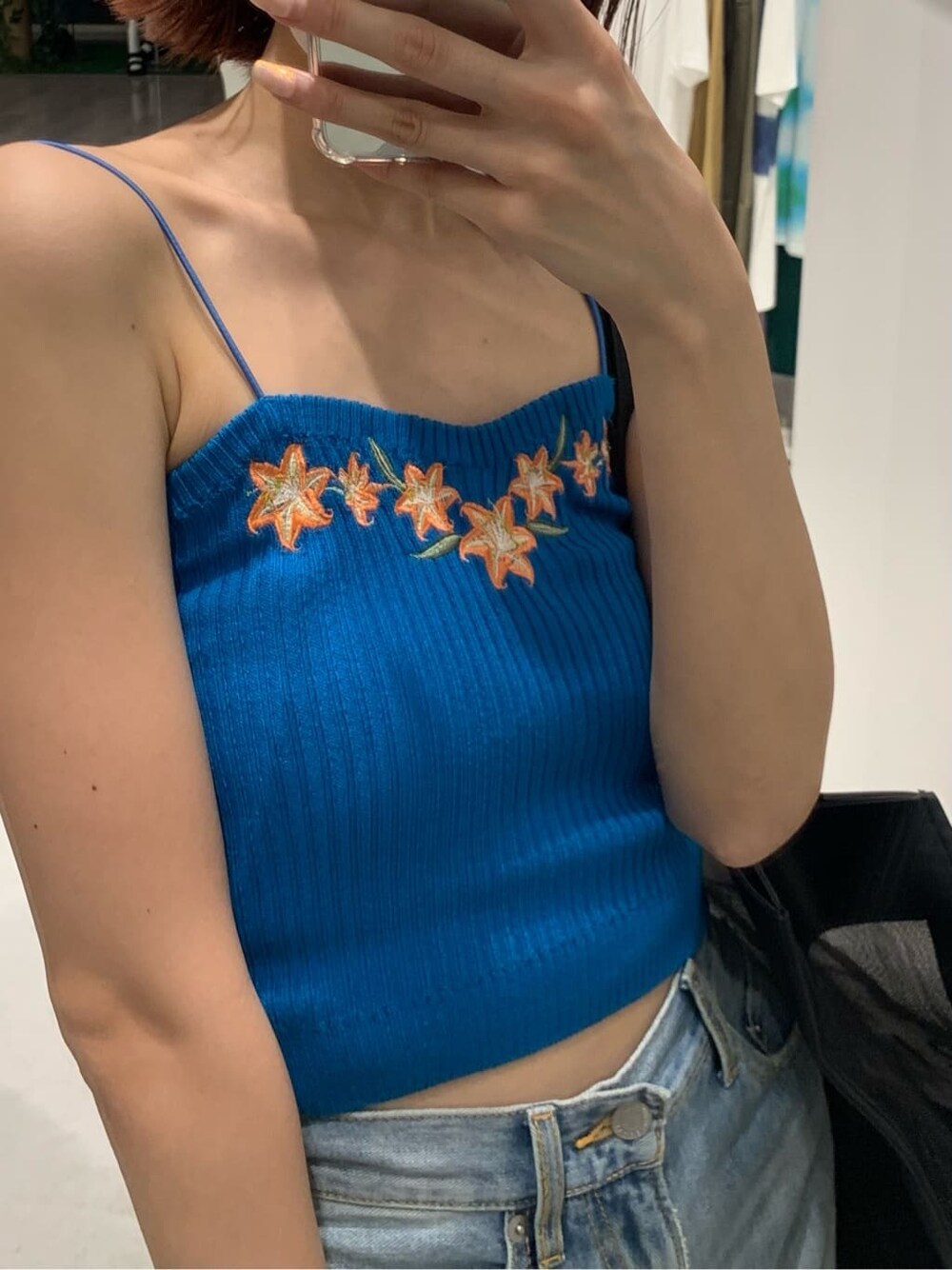 ブラック系のサンダル、ブルー系のデニムパンツ、ブラック系のトートバッグを着用したレディースの夏コーディネートの3枚目の写真