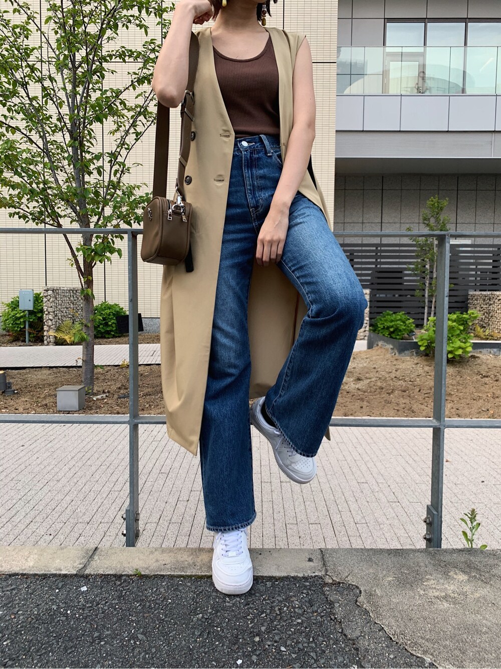 ブルー系のデニムパンツ、ベージュ系のトレンチコート、ブラウン系のタンクトップを着用したレディースの春コーディネートの7枚目の写真