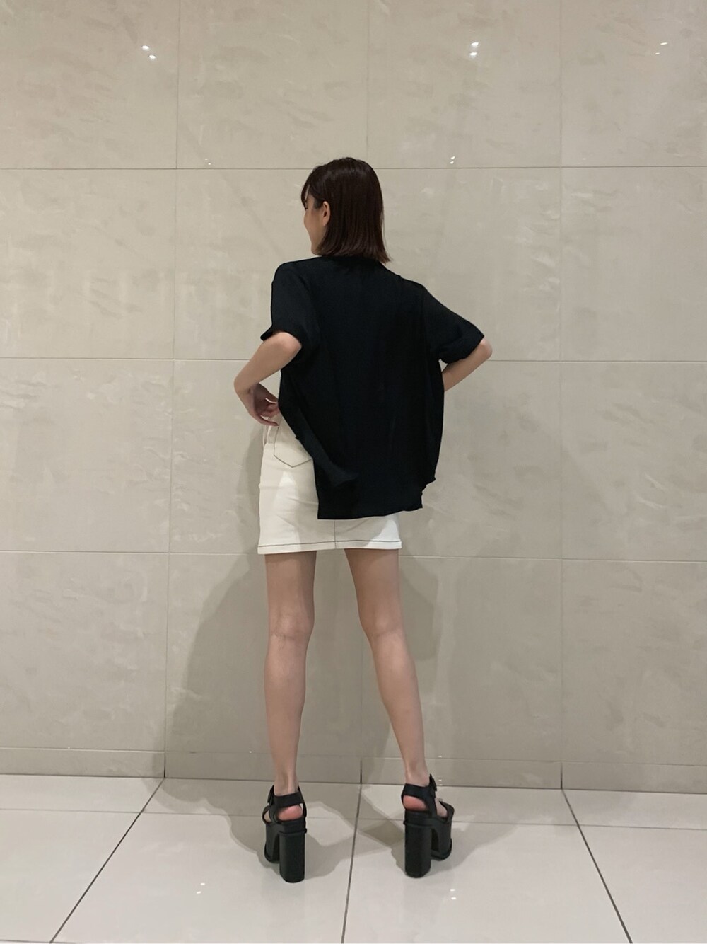 ホワイト系のスカート、ブラック系のサンダル、ブラック系のシャツ/ブラウスを着用したレディースの春コーディネートの2枚目の写真