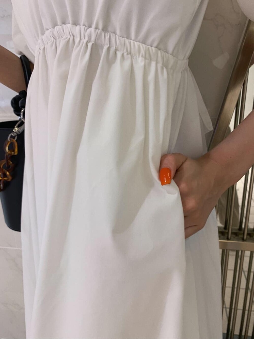 ホワイト系のワンピース、ブラック系のショルダーバッグ、その他のサンダルを着用したレディースの春コーディネートの6枚目の写真