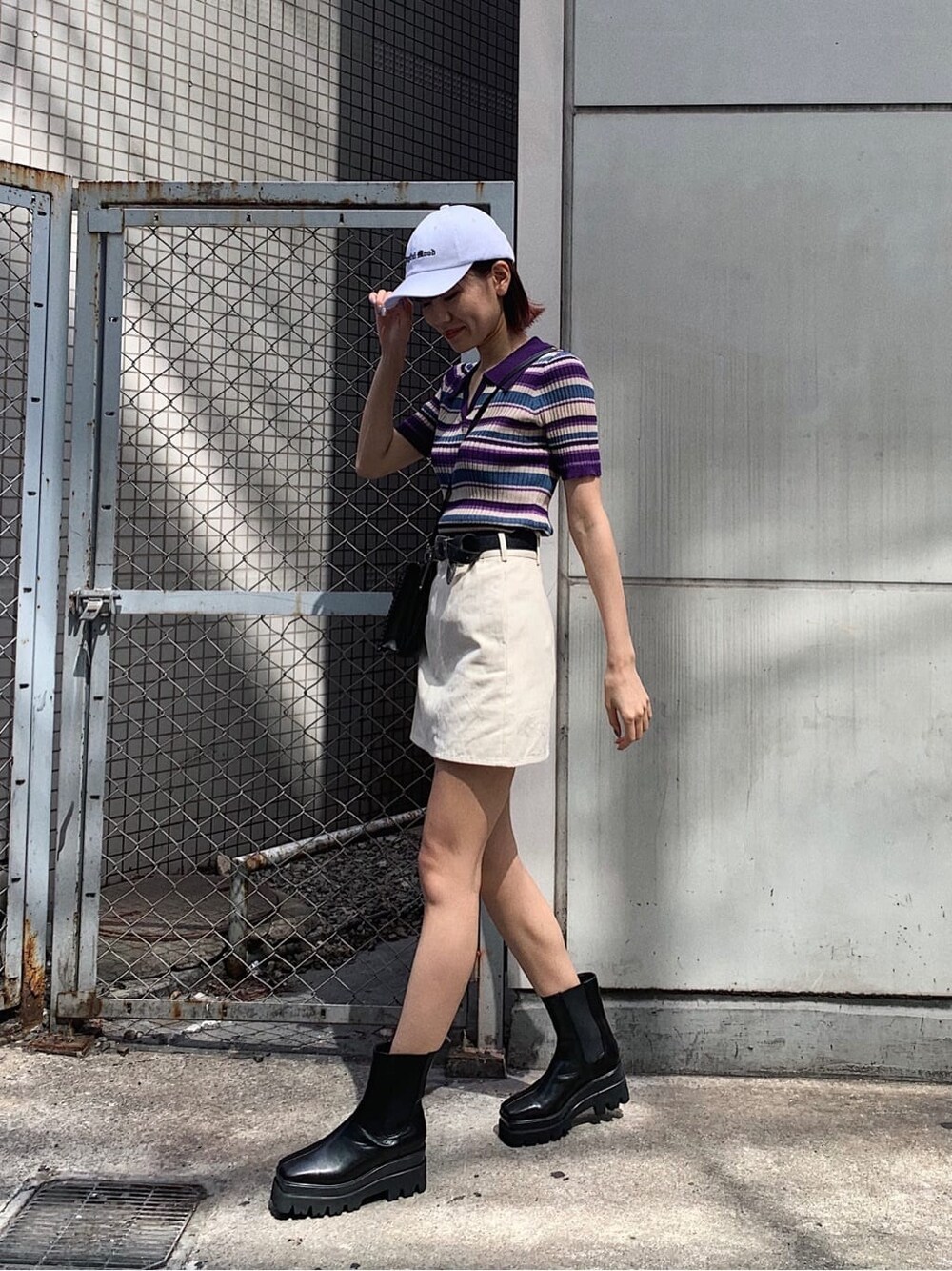 ブラック系のショルダーバッグ、ホワイト系のスカート、パープル系のニット/セーターを着用したレディースの春コーディネートの2枚目の写真