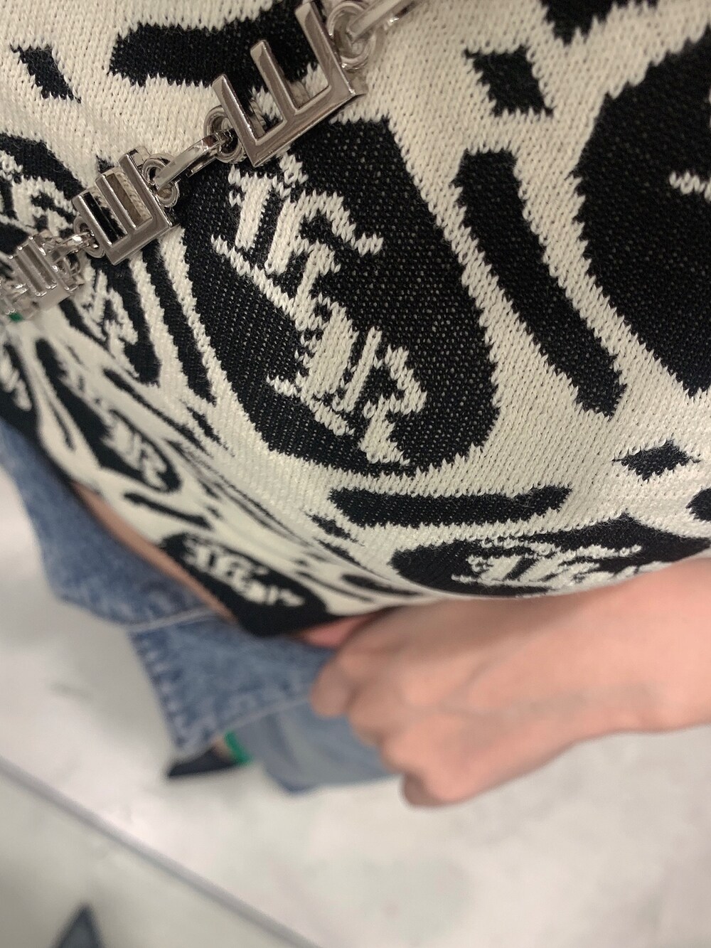 グリーン系のショルダーバッグ、ブルー系のデニムパンツ、ブラック系のニット/セーターを着用したレディースの春コーディネートの6枚目の写真