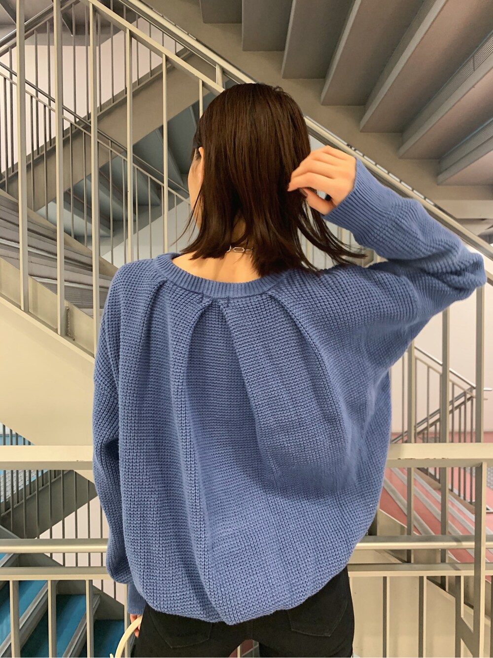 ブラック系のデニムパンツ、ホワイト系のショルダーバッグ、ブルー系のニット/セーターを着用したレディースの冬コーディネートの2枚目の写真