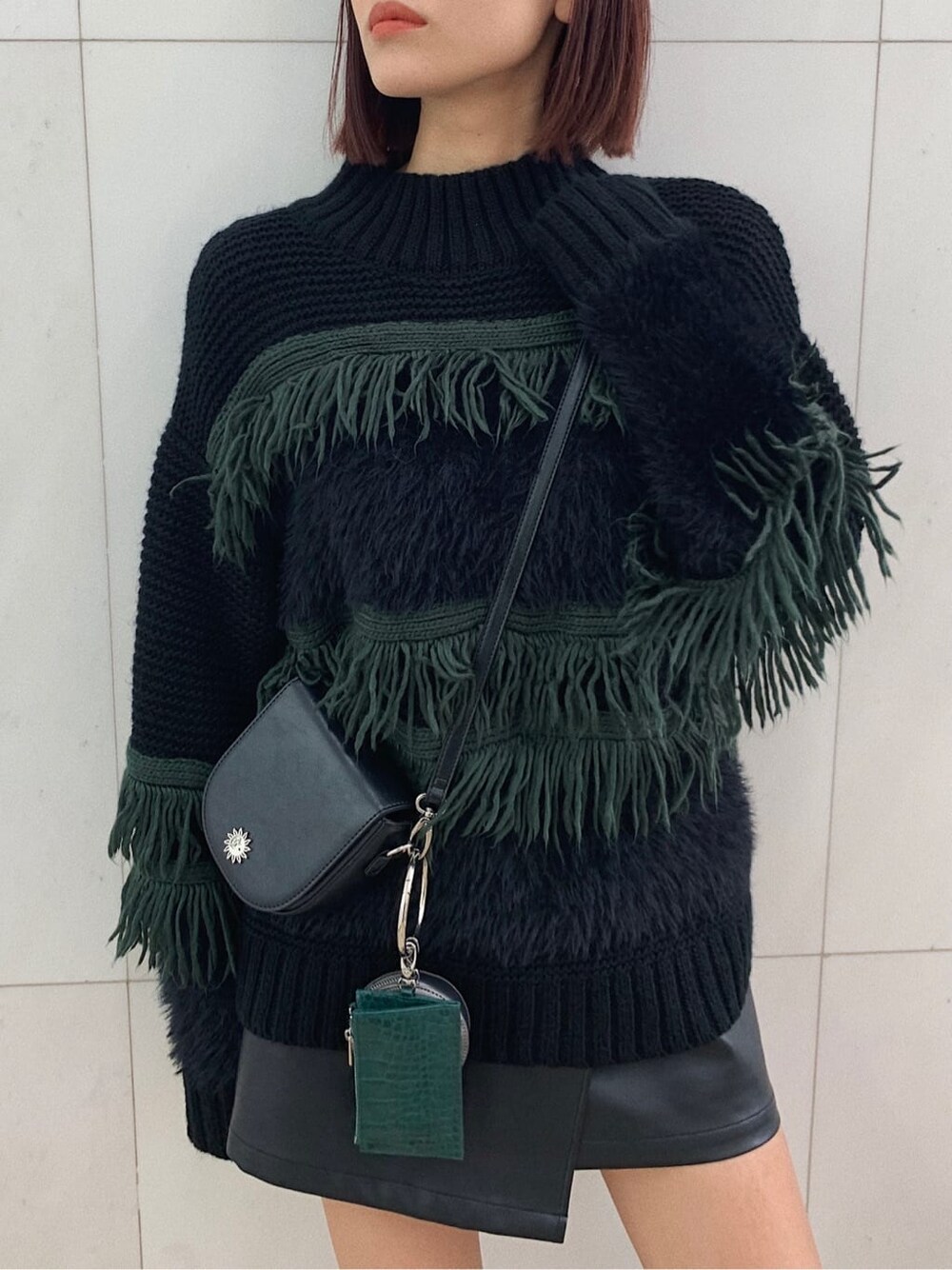 ブラック系のショルダーバッグ、ブラック系のブーツ、ブラック系のスカートを着用したレディースの冬コーディネートの2枚目の写真