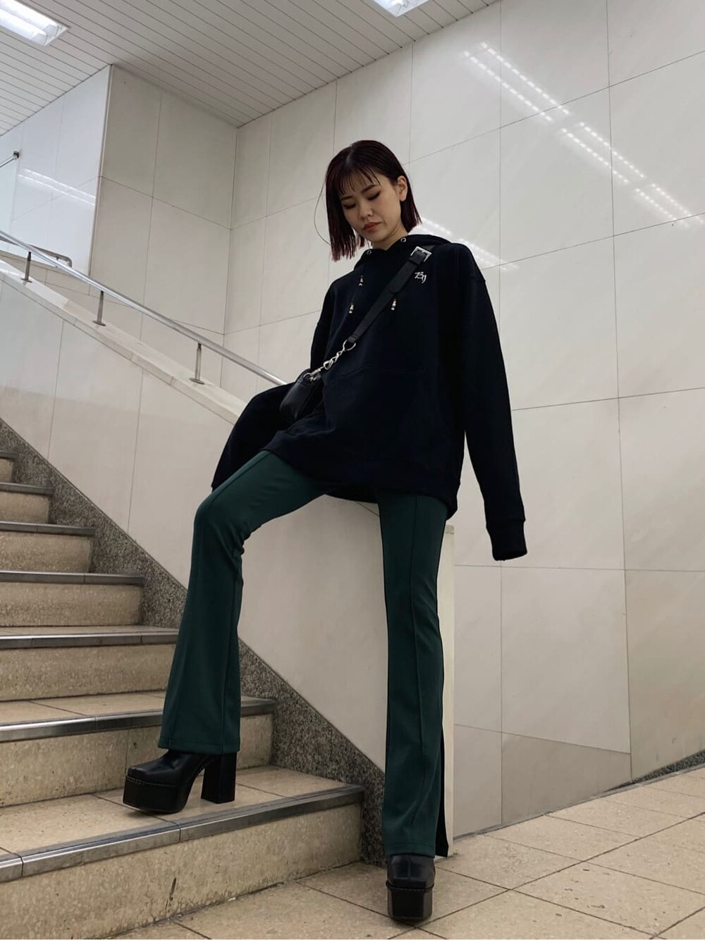 ブラック系のショルダーバッグ、ブラック系のブーツ、ブラック系のパーカーを着用したレディースの秋コーディネートの2枚目の写真