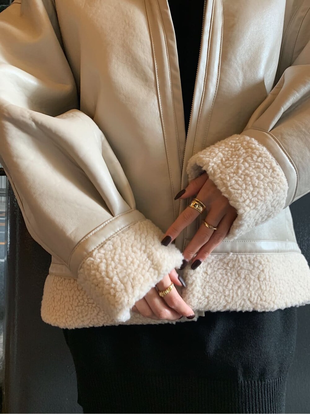 ホワイト系のブルゾン、ブラック系のブーツ、ゴールド系のリングを着用したレディースの冬コーディネートの4枚目の写真