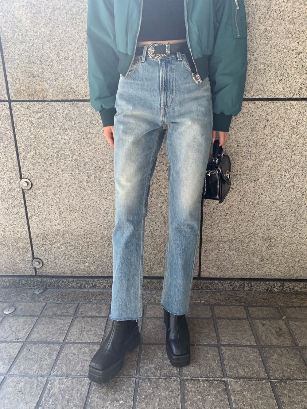 ブラック系のハンドバッグ、ブルー系のデニムパンツ、ブルー系のMA-1を着用したレディースの秋コーディネートの8枚目の写真