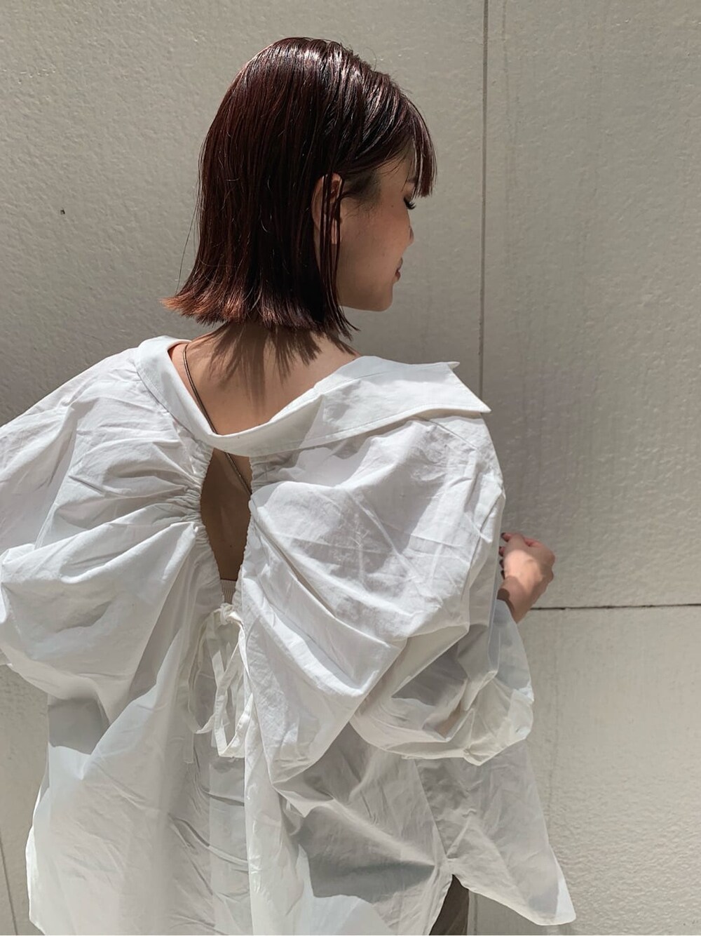 ブラウン系のデニムパンツ、ホワイト系のキャミソール、ブラック系のサンダルを着用したレディースの秋コーディネートの3枚目の写真