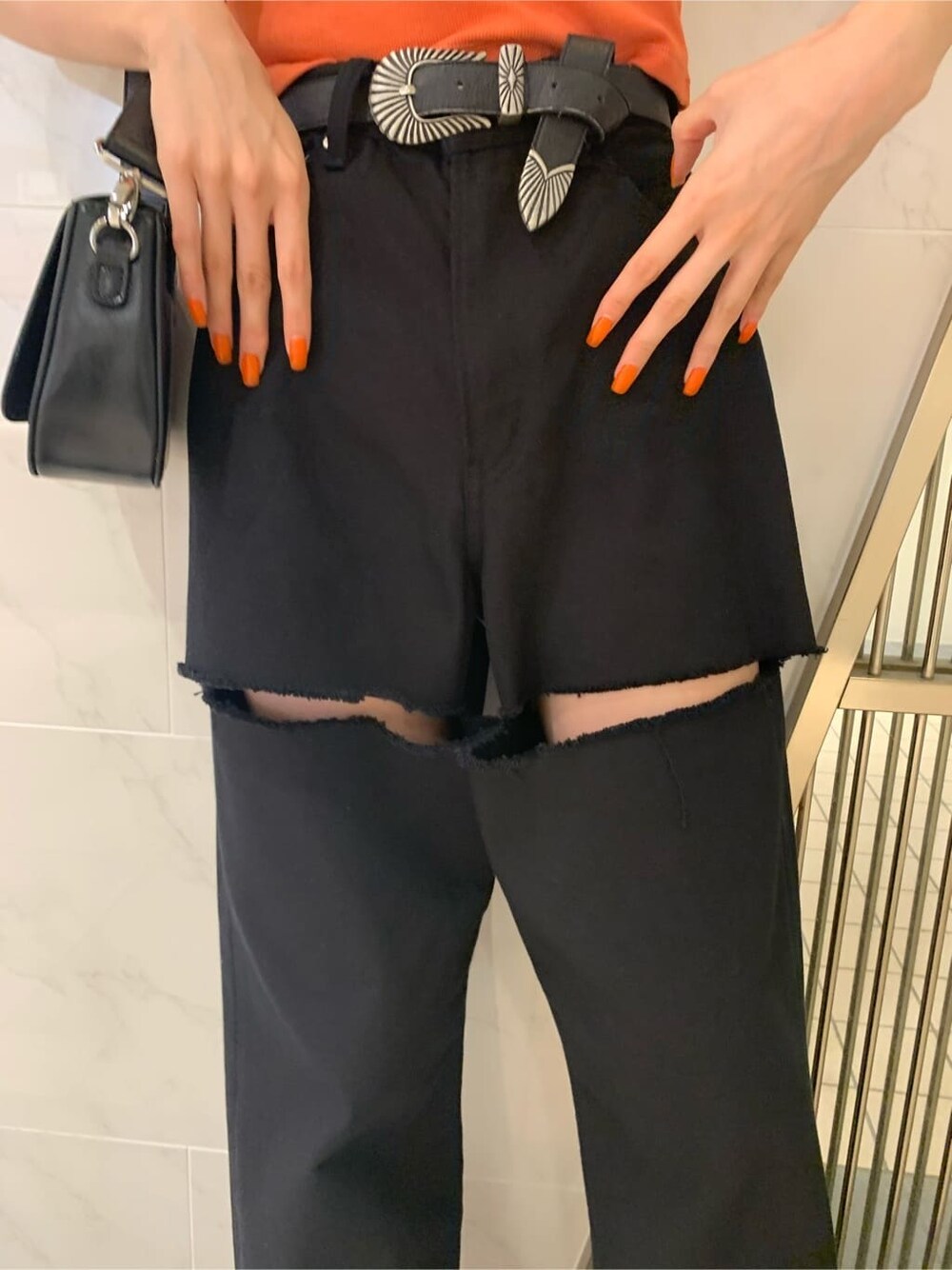 オレンジ系のTシャツ/カットソー、ブラック系のサンダル、ブラック系のショルダーバッグを着用したレディースの春コーディネートの6枚目の写真