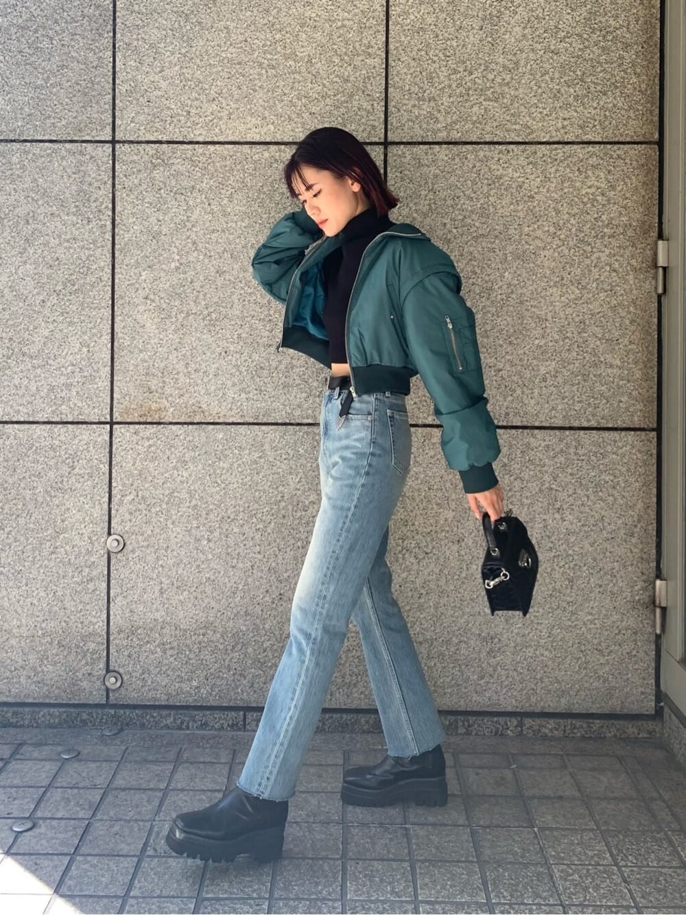 ブラック系のハンドバッグ、ブルー系のデニムパンツ、ブルー系のMA-1を着用したレディースの秋コーディネートの2枚目の写真