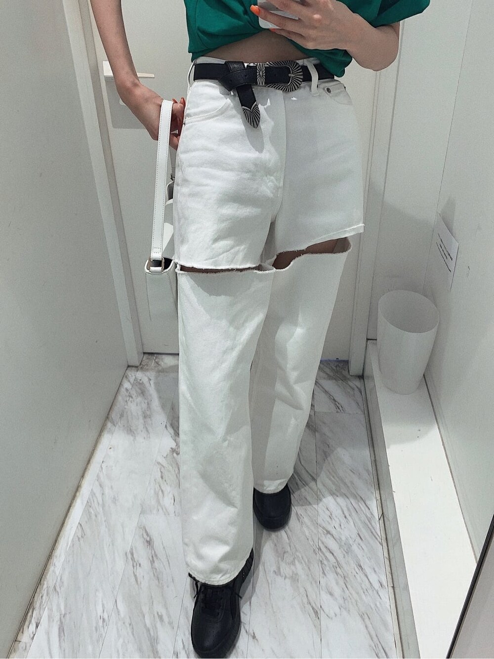 ブラック系のスニーカー、ホワイト系のショルダーバッグ、ホワイト系のデニムパンツを着用したレディースの春コーディネートの5枚目の写真